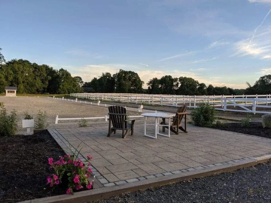 Avastar's outdoor dressage arena seen from the patio, with white paddock fencing beyond